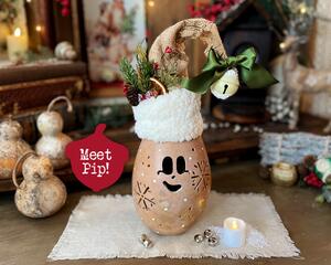 A Christmas elf decoration made from a dried gourd. This gourd, named Pip, has a happy face carved into it and is wearing his won elf hat